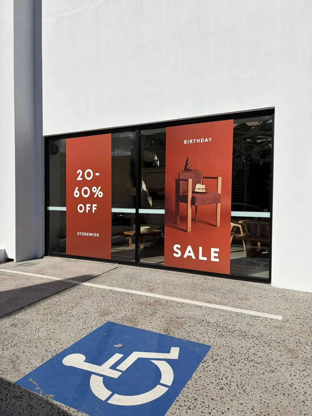 Showroom frontage with a 20 to 60 percent off panel paired with the Birthday Sale artwork panel