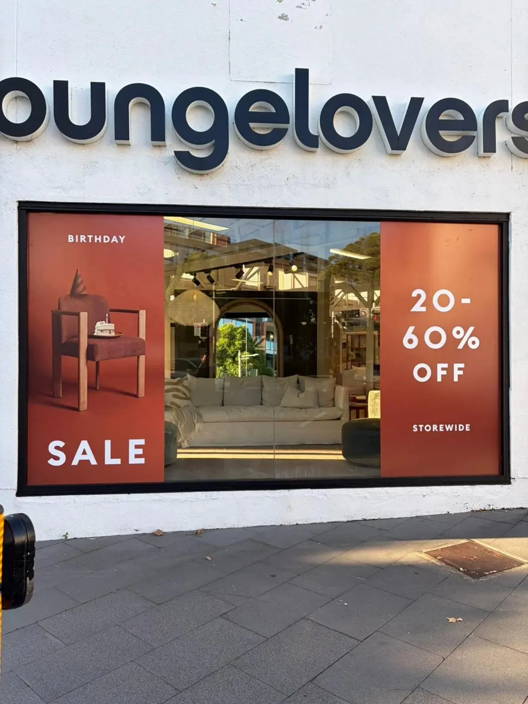 Birthday Sale window panels installed beneath the Lounge Lovers fascia lettering on a showroom frontage