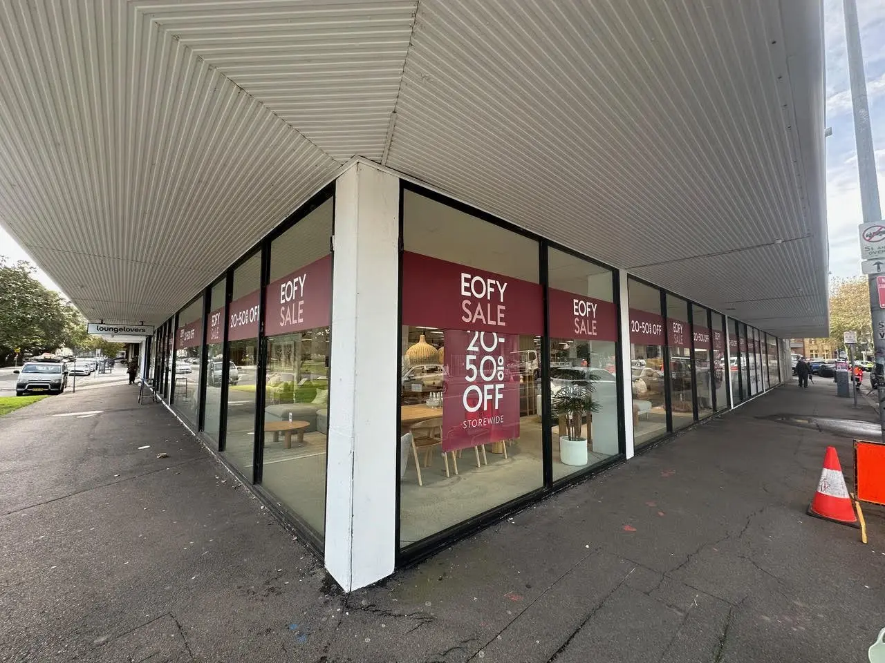 Corner glass showroom with EOFY sale graphics wrapping both faces of the frontage