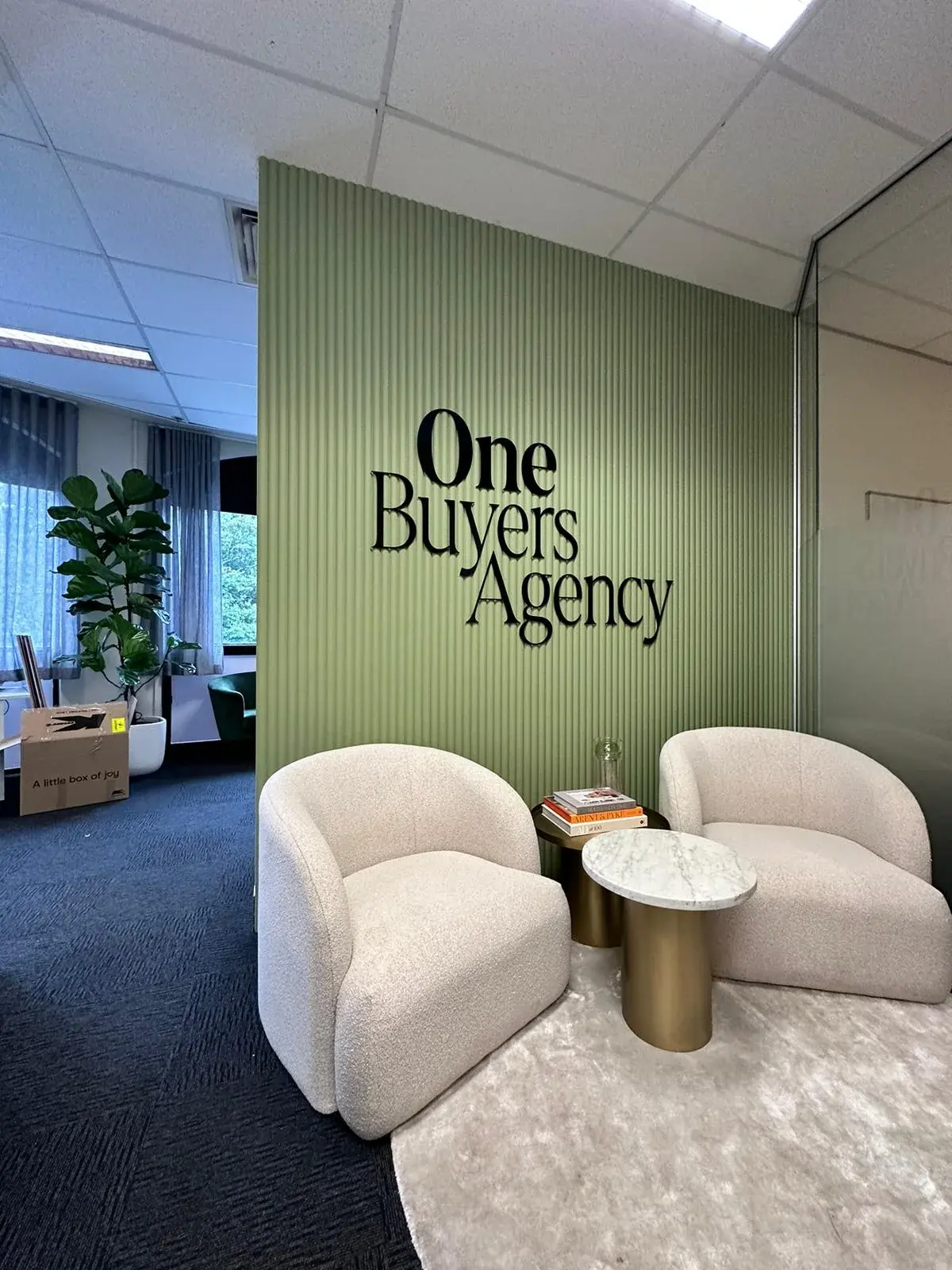 Completed black acrylic One Buyers Agency logo installed on a curved green fluted office wall in Double Bay