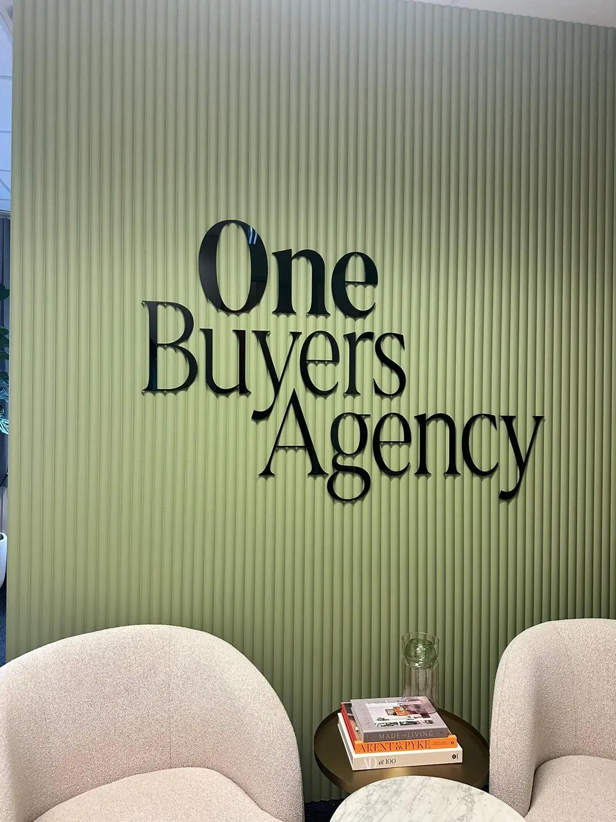 Close completed view of the stacked One Buyers Agency black acrylic logo on the green fluted wall