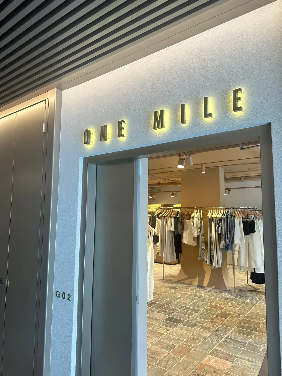 Warm halo illuminated ONE MILE dimensional letters installed above the entry to the Bondi Beach boutique