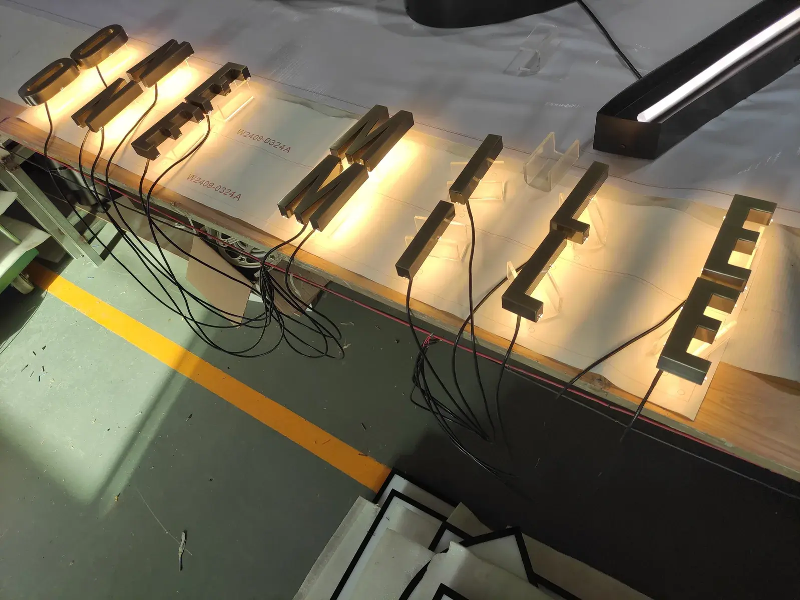Individual warm halo illuminated ONE MILE letters arranged for a workshop light test before installation