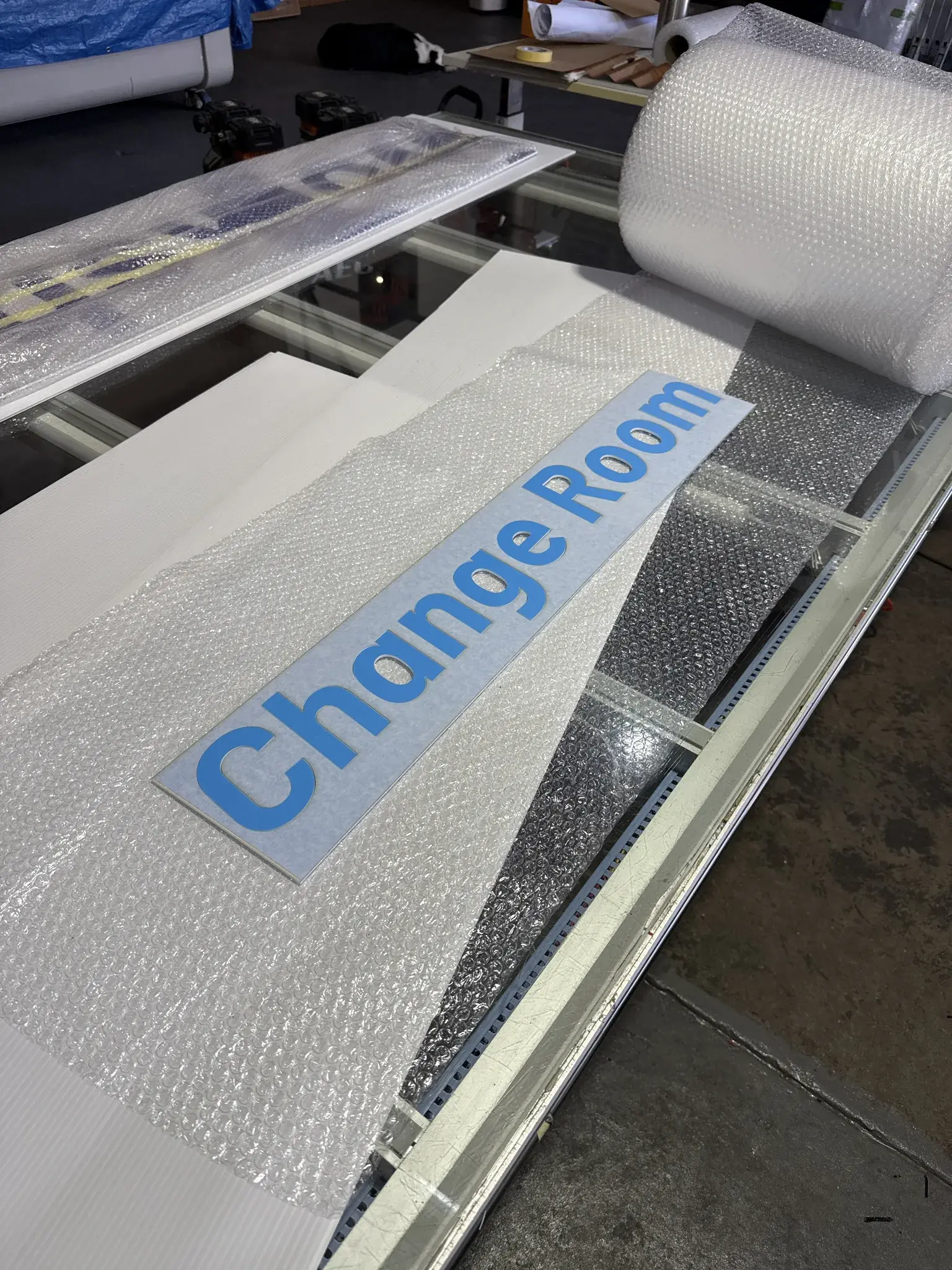 Cut Change Room lettering laid out and wrapped in the workshop ahead of installation