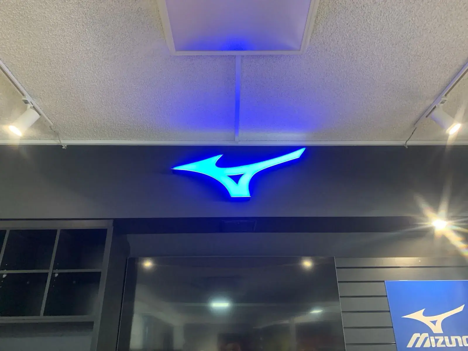 Blue illuminated Mizuno logo glowing against the dark bulkhead above the department