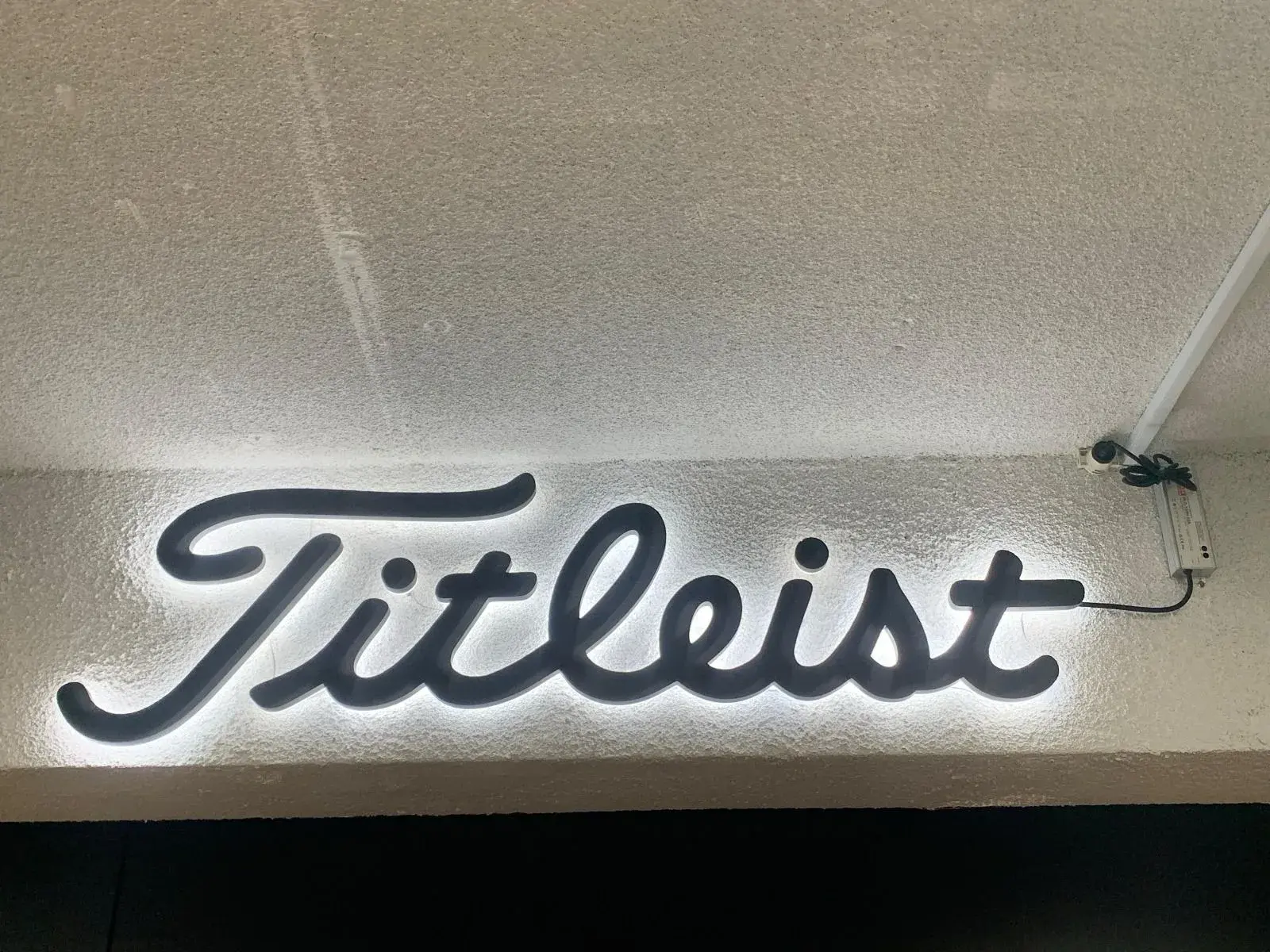 Titleist script sign glowing with a white halo after installation above the department