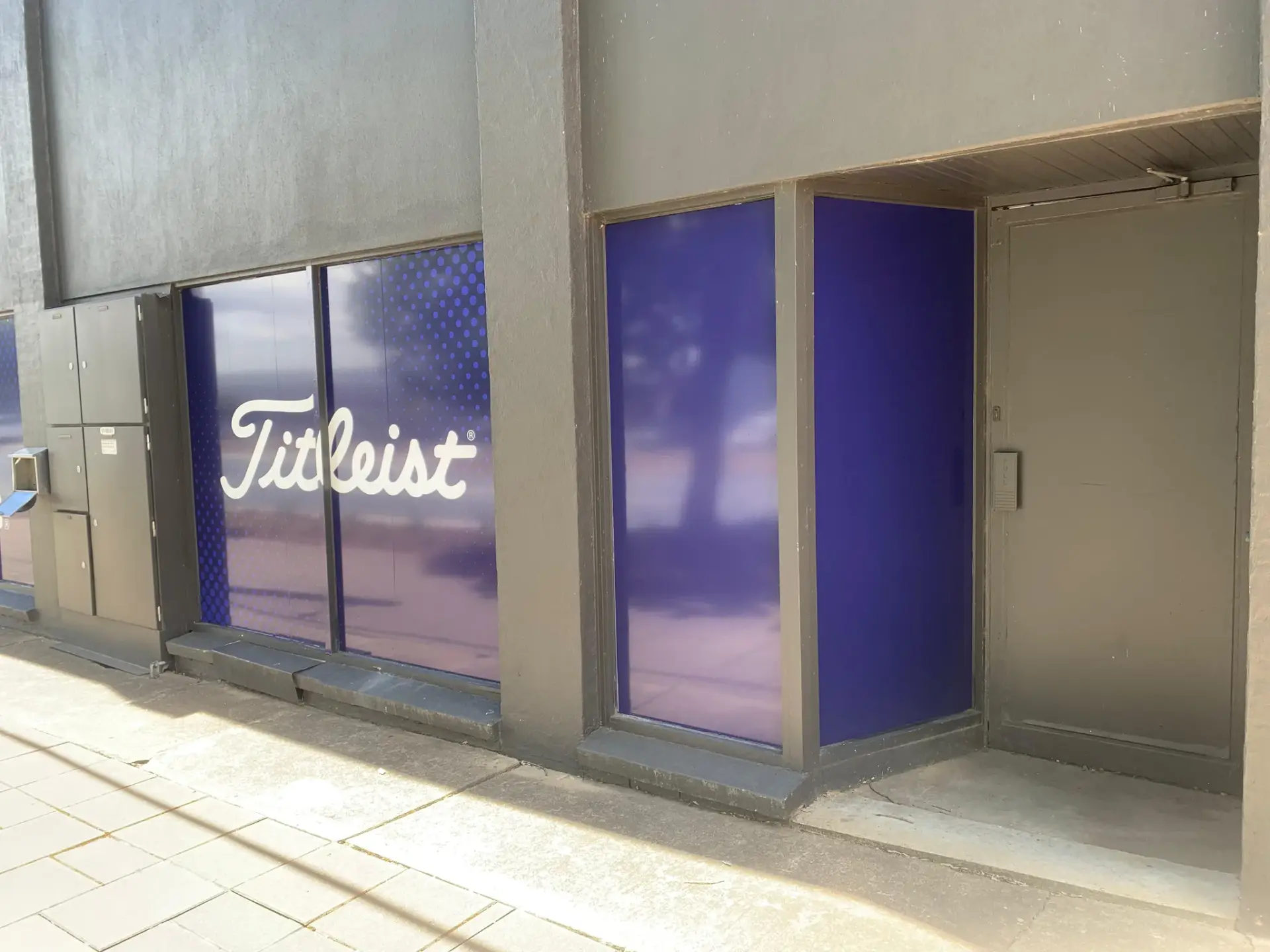 Titleist window graphic wrapping the glazing beside the recessed store entry