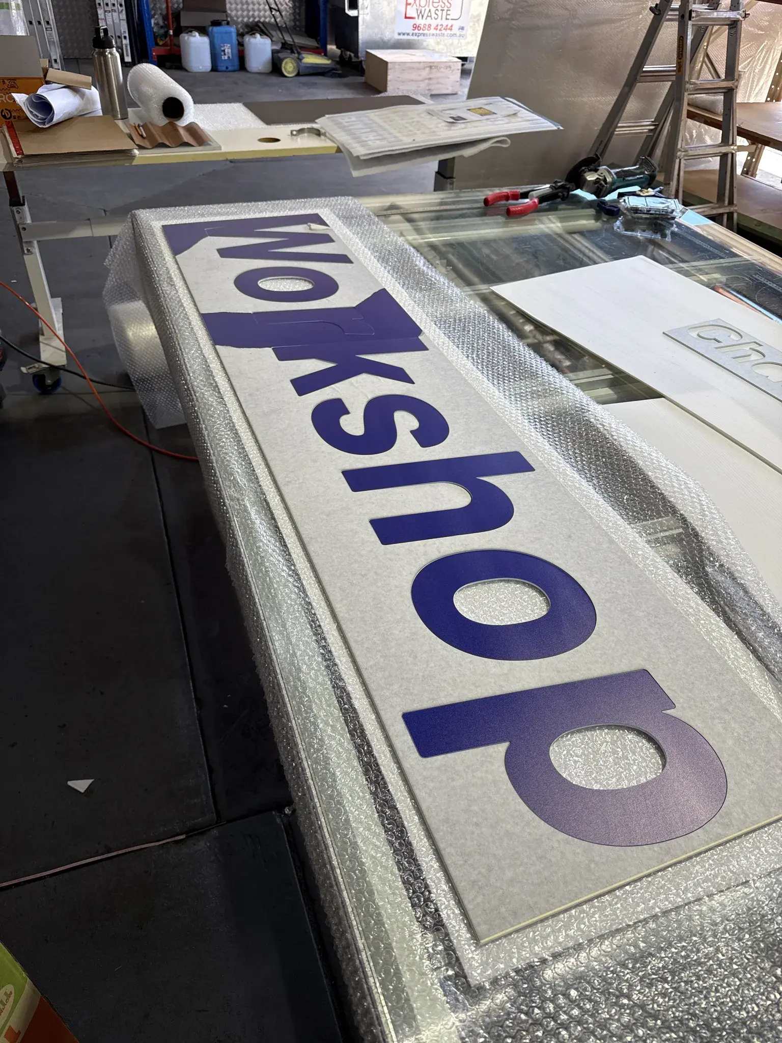 Workshop directional sign protected in wrap during production before the store fit-off