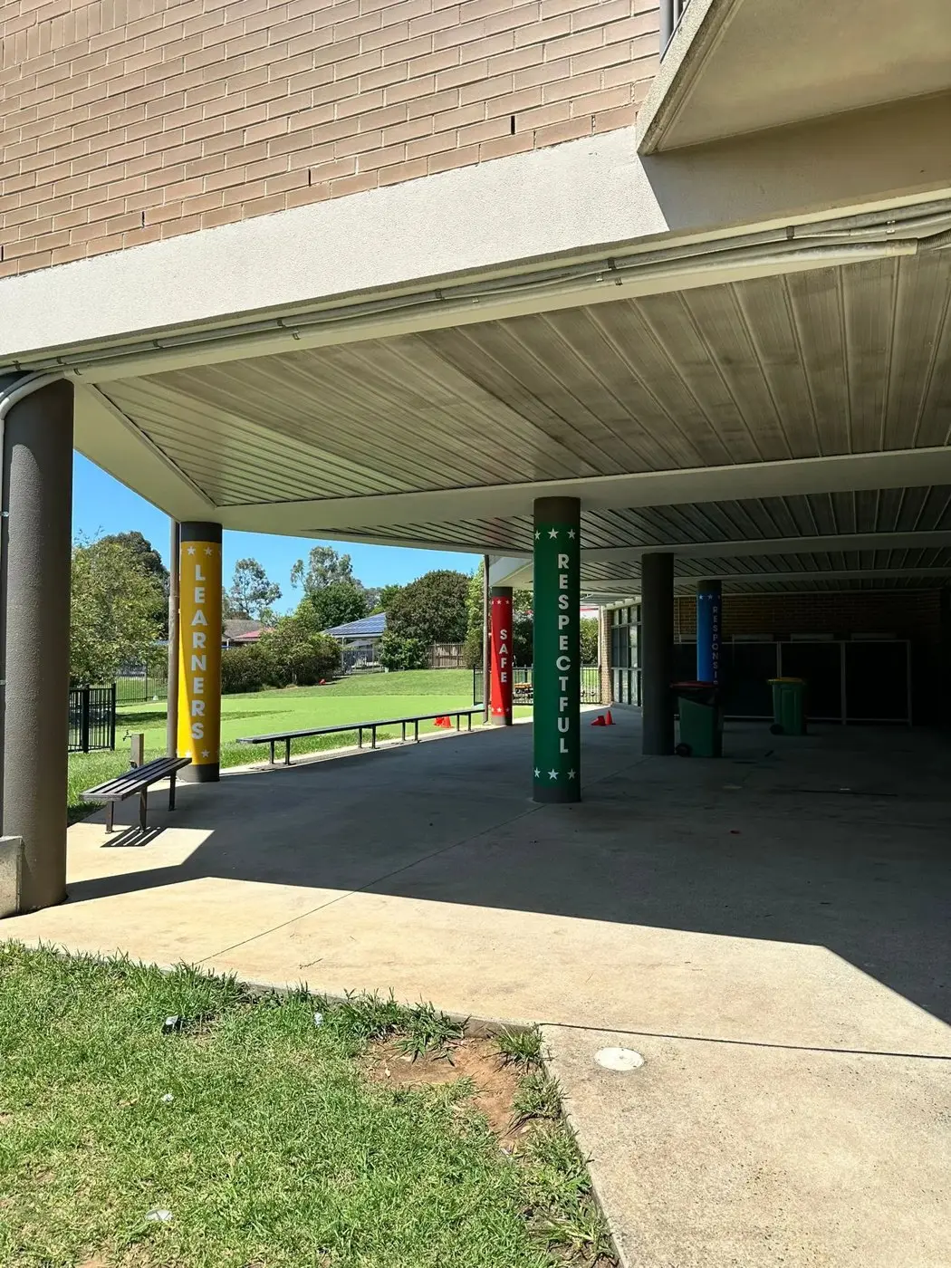 Covered walkway with school columns wrapped in coloured values graphics beside the playground