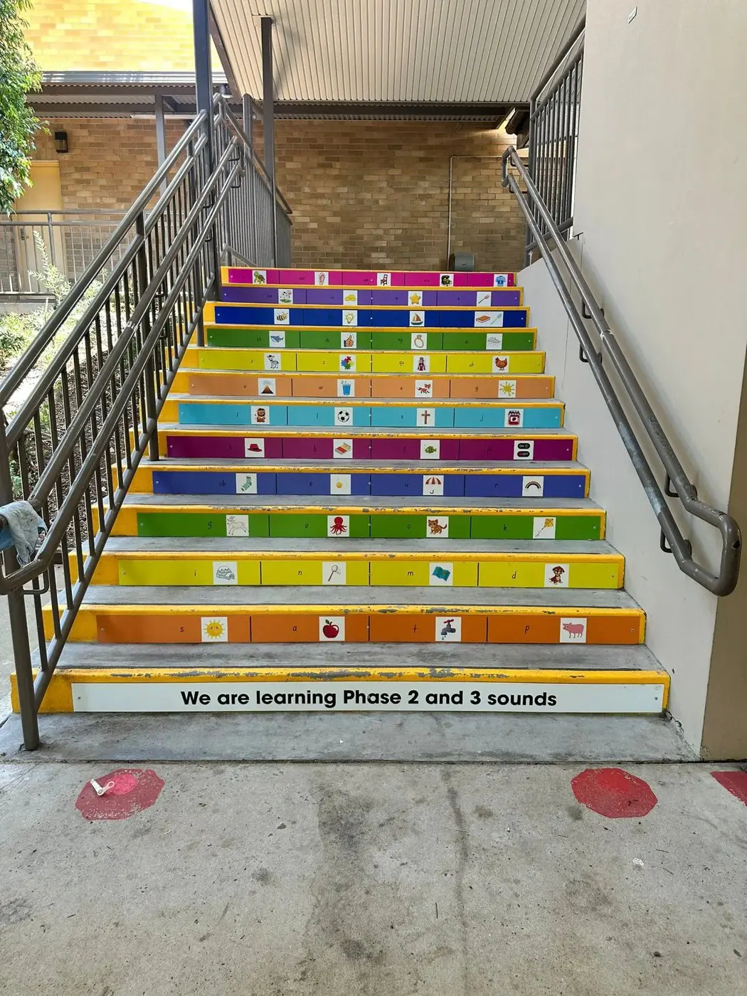 Colourful staircase printed with phonics sounds and pictures, labelled We are learning Phase 2 and 3 sounds