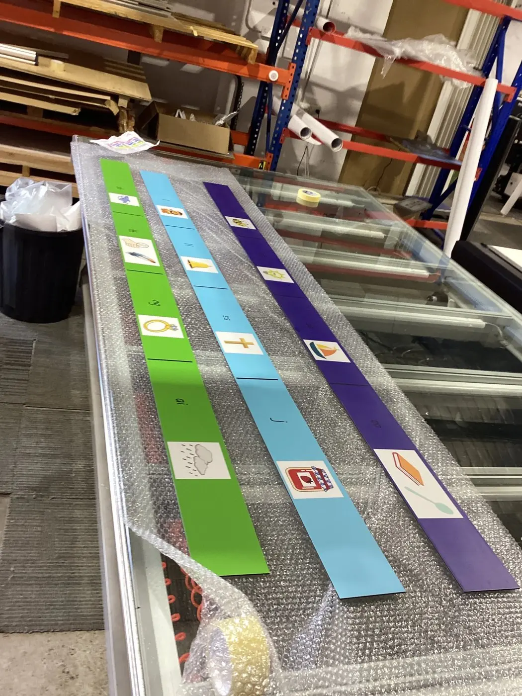 Printed and laminated stair and wall graphic strips laid out on the Platinum Signs workbench before delivery