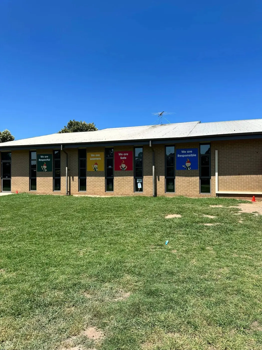 Wide view of a school building with values graphics visible across its windows and walls from the oval