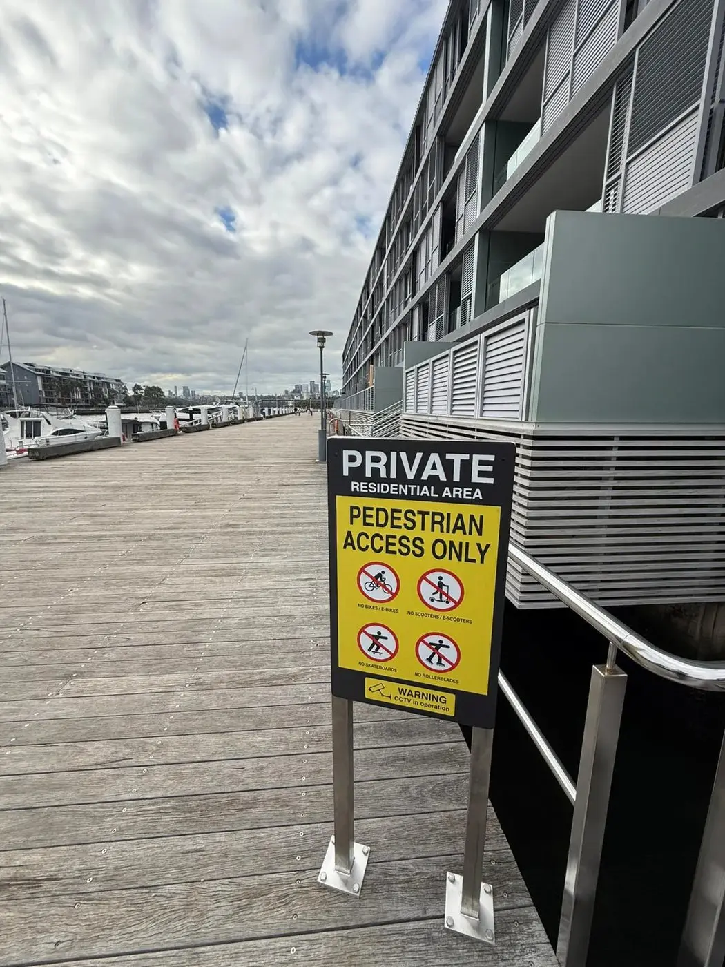 Pedestrian access only sign mounted on twin posts at a building corner of the wharf complex