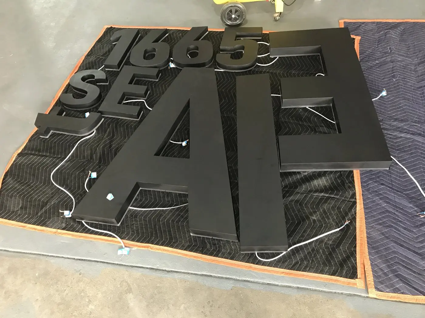 Numerals and letters for the Est 1965 line laid out on blankets before installation