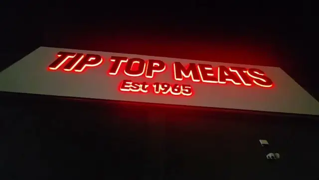 Tip Top Meats Est 1965 halo-illuminated 3D letters glowing red at night on the Laverton North building
