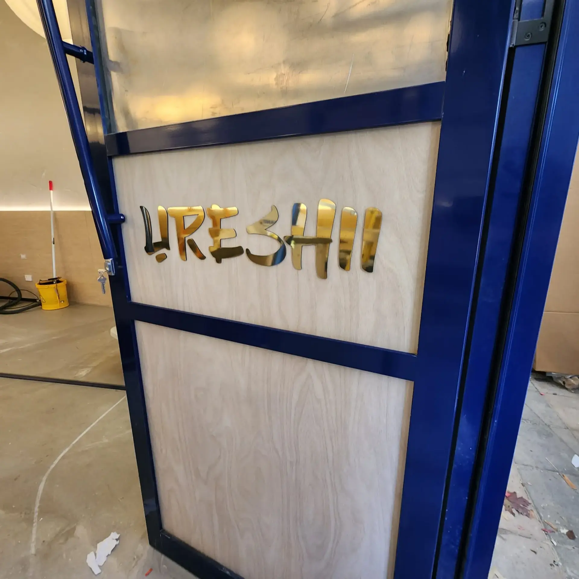 Mirror-gold dimensional Ureshii lettering fitted to a timber-look interior panel