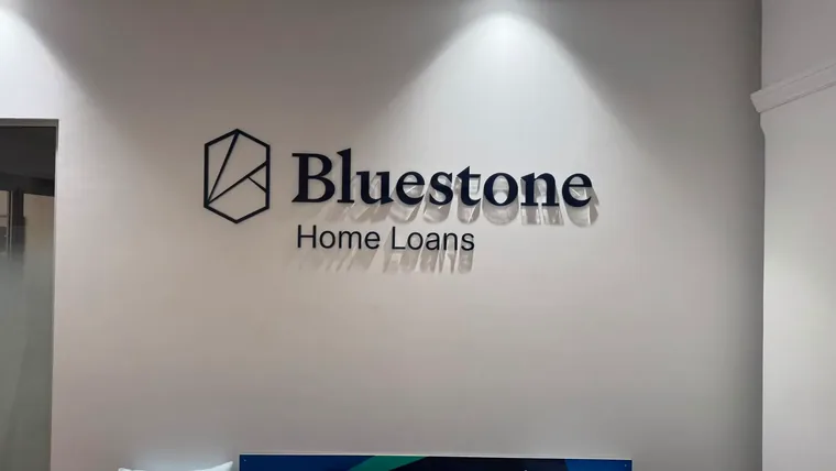 Bluestone Home Loans dimensional navy lettering and hexagonal logo mark on a white reception wall under a downlight