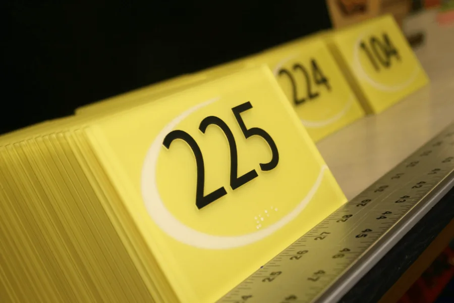 Yellow coloured acrylic number signs with black digits, stacked on a workbench