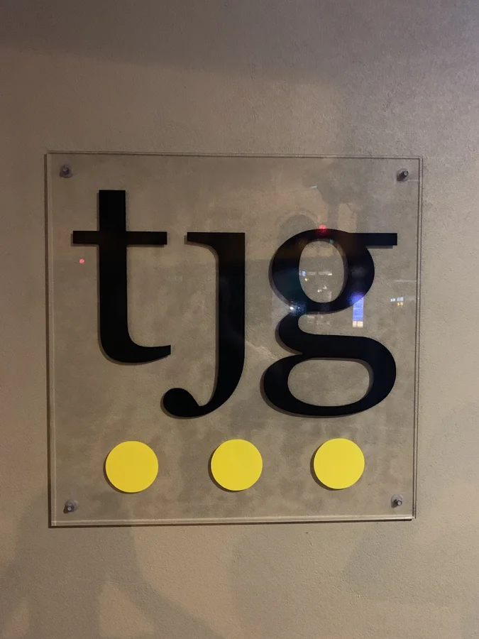 Clear acrylic plaque with black lettering and yellow discs, mounted on stand-off fixings
