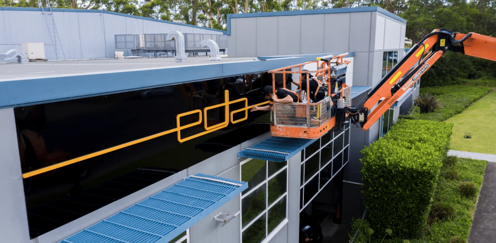 Installers fitting EDA facade signage from an elevated work platform